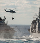 H-60 flies between T-AOE-6 USNS Supply, CG 72 USS Vella Gulf